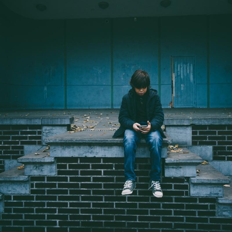 Chłopiec z telefonem na schodach