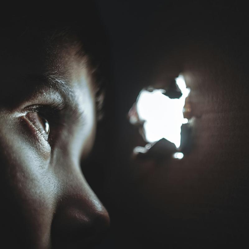 Osoba patrze przez dziurę